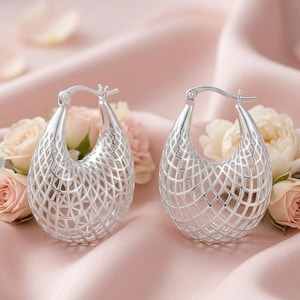 May include: A pair of silver hoop earrings featuring a prominent openwork lattice or grid pattern. The earrings have a teardrop-shaped silhouette and a polished metallic finish, designed with a hinged post mechanism for secure closure.