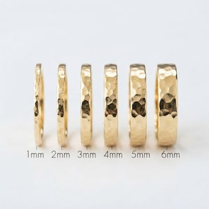 May include: Six gold-toned rings with a hammered texture, arranged in increasing order of width from 1mm to 6mm. Each ring features a reflective, faceted surface and is labelled with its corresponding width measurement in millimetres below it.