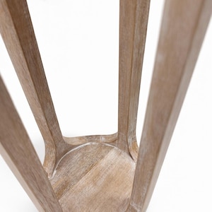 May include: A wooden stool with a light brown finish. The stool has a round seat and four curved legs that splay outwards. The wood grain is visible, and the stool appears to be lightly distressed.