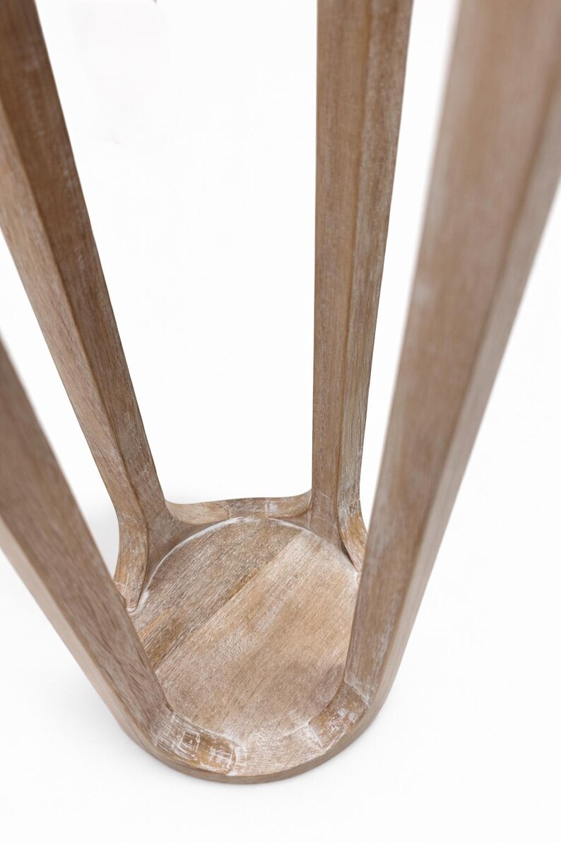 May include: A wooden stool with a light brown finish. The stool has a round seat and four curved legs that splay outwards. The wood grain is visible, and the stool appears to be lightly distressed.