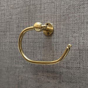 Peut inclure: Un porte-serviettes en laiton avec un design circulaire. L'anneau est monté sur une base ronde avec des trous de vis. Le design général est de style classique et élégant. La finition est de couleur or brillant.