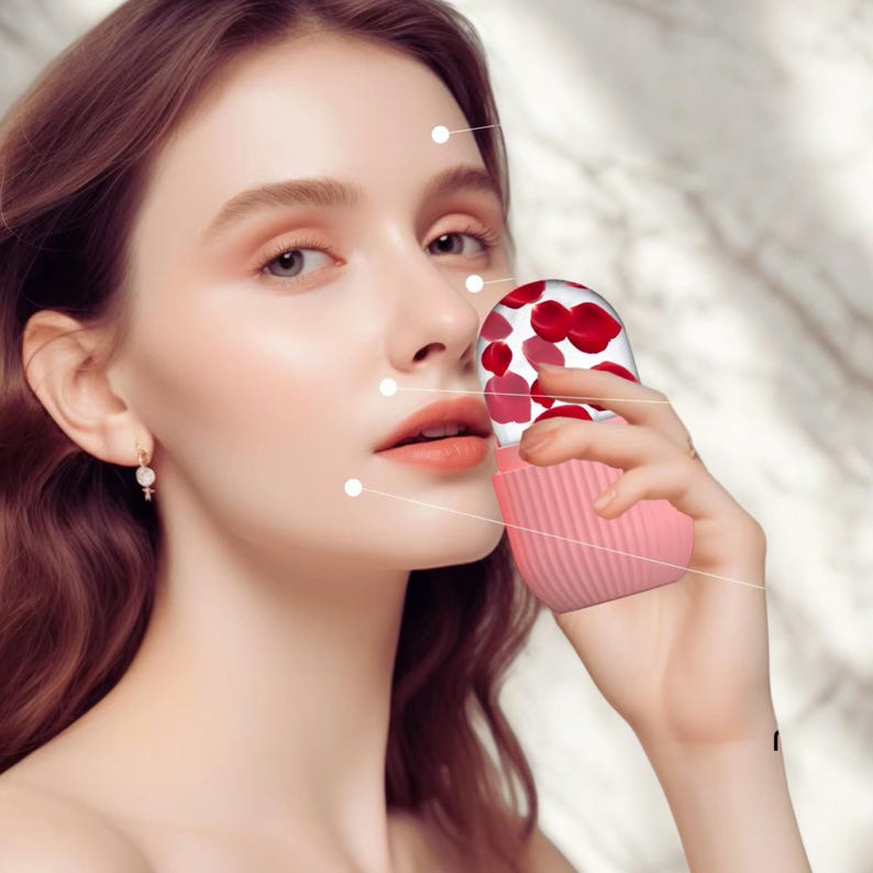 K&ouml;nnte beinhalten: Ein rosa Sch&ouml;nheitswerkzeug mit einem transparenten Deckel, der mit roten Rosenbl&auml;ttern gef&uuml;llt ist. Das Werkzeug hat einen gerippten Boden und wird in der N&auml;he des Gesichts einer Person gehalten. Der Hintergrund ist ein weiches, verschwommenes Marmormuster.