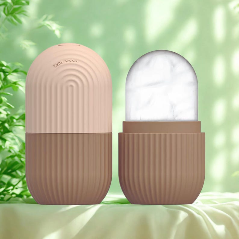 K&ouml;nnte beinhalten: Zweiteilige Gesichts-Eisroller in einer sanften Farbpalette. Die obere H&auml;lfte ist hellpfirsichfarben mit einem geschwungenen Design, und die untere H&auml;lfte ist braun mit vertikalen Linien. Die zweite Rolle ist offen und zeigt ein wei&szlig;es, eisiges Inneres.