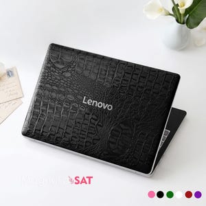 May include: A black laptop skin featuring a textured crocodile skin pattern applied to the lid of a Lenovo laptop. The surface has a glossy finish with a repeating scale design. The silver Lenovo logo is visible in the centre of the laptop lid.