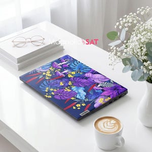 May include: A closed laptop featuring a vibrant botanical skin with a dark blue background, purple and blue monstera leaves, small yellow flowers, red stalks, and purple mushrooms. The Lenovo brand logo is visible on the bottom right corner.