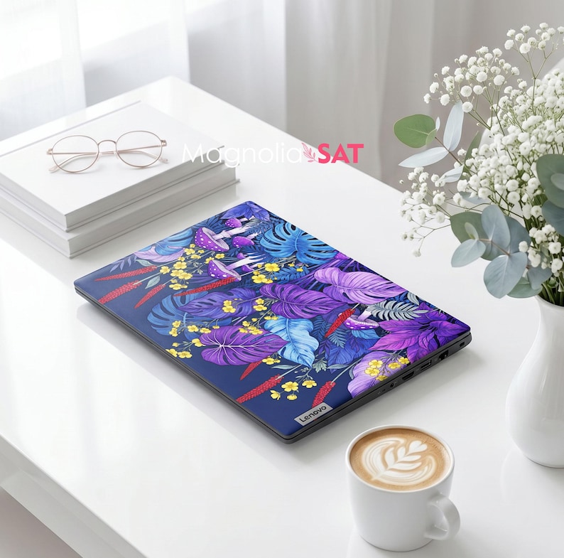 May include: A closed laptop featuring a vibrant botanical skin with a dark blue background, purple and blue monstera leaves, small yellow flowers, red stalks, and purple mushrooms. The Lenovo brand logo is visible on the bottom right corner.