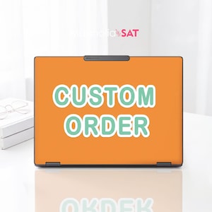 Könnte beinhalten: Ein Laptop mit einer einfarbigen orangefarbenen Hülle, die den Text CUSTOM ORDER in fetten, hellgrünen Großbuchstaben mit weißem Rand zeigt. Der Markenname magnolia SAT steht in kleiner Schrift über dem Bildschirm. Der Laptop steht auf einer weißen Fläche.
