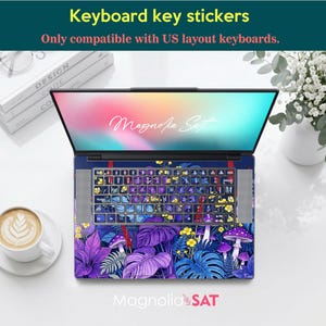 May include: A laptop featuring a keyboard skin and palm rest decal with a vibrant botanical pattern of purple and blue leaves, yellow flowers, and mushrooms. The screen displays the text Magnolia Sat. The stickers are for US layout keyboards.