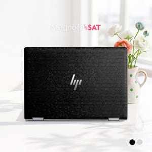 May include: A black laptop with a textured honeycomb pattern on the lid and a silver HP logo in the centre. The text Magnolia SAT is visible above the laptop, and a white ceramic pitcher with green polka dots holds white and peach flowers.