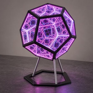 May include: A dodecahedron-shaped infinity mirror lamp with a black frame and internal LED strips emitting a vibrant purple and blue light. The geometric structure is supported by a silver-toned tripod stand attached to a black hexagonal base.