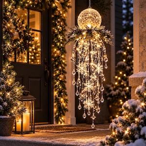 May include: A hanging spherical light fixture with a crackled glass texture, adorned with a ring of pine branches, cascading warm white LED fairy lights, and dangling clear acrylic snowflake and teardrop-shaped crystals for holiday decor.