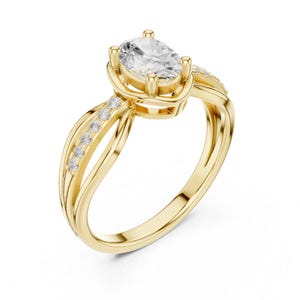 May include: A gold ring featuring a central oval-cut clear gemstone held in a four-prong setting. The band is split into two delicate, intertwining strands, with one strand accented by a row of small, round, clear pavé-set stones.