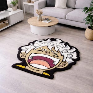 Peut inclure: Un tapis de style cartoon représentant un personnage avec une bouche grande ouverte et des cheveux blancs bouclés. Le tapis a une bordure noire avec des accents jaunes et est posé sur un sol en bois clair. La bouche du personnage est ouverte, révélant un intérieur rose.