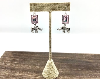 May include: A pair of silver dangle earrings with pink crystal stones and elephant charms.