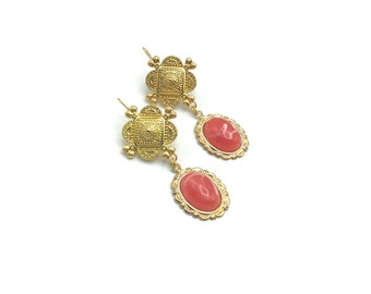 May include: Gold tone earrings with a detailed square design and a pink oval stone.