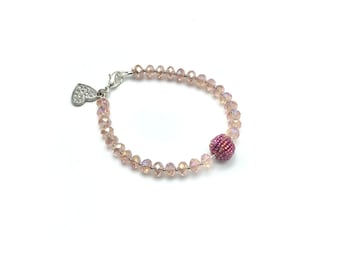 May include: A pink crystal bracelet with a heart charm and a large pink crystal bead.