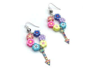 May include: A pair of dangle earrings featuring colorful flower beads in pink, blue, yellow, and purple. Each earring has a silver hook and a decorative arrow charm with a geometric pattern.