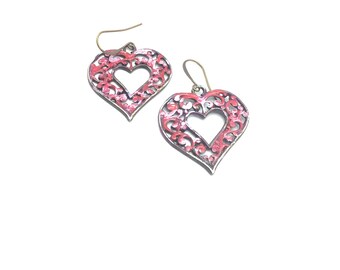 May include: A pair of silver heart-shaped earrings with a pink filigree design.