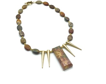 May include: A gold necklace with a rectangular pendant made of brown and gold stone. The necklace is made of oval-shaped brown and gold stones. The pendant has gold spikes on the bottom.
