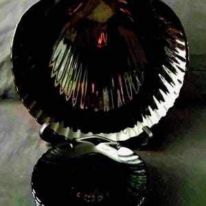 Op de afbeelding: Een set zwarte, schelpvormige serveerschalen. De grote schaal staat op een standaard, met een kleinere stapel bijpassende schalen eronder. Het glanzende oppervlak reflecteert licht en benadrukt de getextureerde randen en het algehele ontwerp.