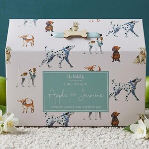 Può includere: Una scatola regalo rettangolare bianca con un motivo ripetuto di varie razze canine. La scatola presenta una maniglia azzurra con un dettaglio in legno a forma di osso. Un'etichetta centrale color ottanio riporta: The Wildlife, Ling Design, Apple and Jasmine.