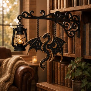 May include: A black metal wall bracket with scrollwork supports a hanging black lantern and a wooden dragon cutout. The dragon features a black finish with gold-toned celestial details, including stars and a crescent moon, suspended by two metal chains.