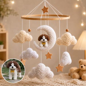 May include: A nursery mobile featuring a circular wooden frame with hanging white crocheted clouds, wooden stars, and a central white crocheted crescent moon holding a small brown and white plush puppy with a yellow bone-shaped tag.