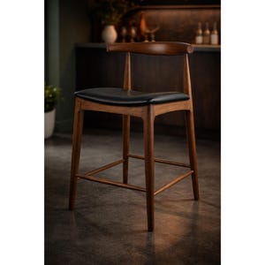 May include: A wooden bar stool with a curved backrest and a black leather seat. The stool has a warm brown finish and a footrest. The design is modern and minimalist, suitable for a kitchen or bar setting.