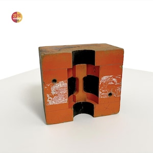 May include: Orange wooden block with a cross-section revealing an internal structure. The block has a rectangular shape with a central cavity and the number "2" visible. The vintage item has some white paint marks and the logo "20 90 vintage".