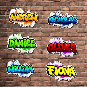 May include: Six graffiti-style name stickers on a brick wall. The names are "Andrew", "Nicholas", "Daniel", "Oliver", "William", and "Fiona", each in a unique color scheme with a splash effect. The background is a textured brick wall.