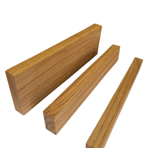 May include: Three rectangular wooden blocks of varying sizes are arranged against a white background. The wood has a light brown color with visible grain patterns. The blocks are cut with clean, straight edges, suggesting they are for construction or craft projects.