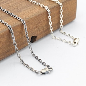 Può includere: Due catene in metallo, una con finitura argento brillante e una con finitura argento ossidato scuro. Entrambe le catene presentano un classico design a maglie ovali uniformi e una chiusura a moschettone sicura all'estremità di ogni catena.