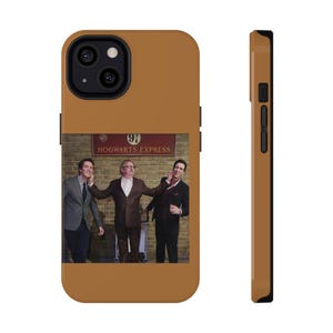 May include: A brown phone case featuring a photo of three men in suits posing in front of a sign that reads "Hogwarts Express". The case has a black camera lens cutout and a black side button.