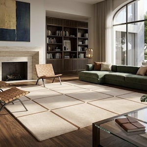 May include: A modern living room with a green sectional sofa, woven leather chairs, and a large area rug. A fireplace and built-in bookshelves add to the room's elegance. A large window offers a view of the outdoors.