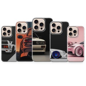 Puede incluir: Cinco fundas para smartphone con ilustraciones de automóviles. Los diseños incluyen la parte trasera de un coche deportivo blanco, una silueta de coche al atardecer naranja, un coche blanco de frente, un coche blanco con ruedas azules y el perfil lateral de un coche deportivo rosa.