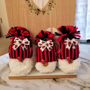May include: Three red and black striped gnome ornaments with white pom-pom beards and ladybug accents.