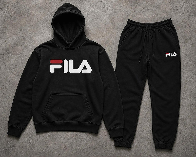 Puede incluir: Conjunto negro de sudadera con capucha y pantal&oacute;n de ch&aacute;ndal Fila. La sudadera con capucha presenta el logotipo de Fila en blanco con un acento rojo. El pantal&oacute;n de ch&aacute;ndal tiene cintura el&aacute;stica y el logotipo de Fila en blanco.