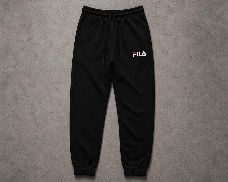 Puede incluir: Pantal&oacute;n deportivo negro con cintura el&aacute;stica y cord&oacute;n. El logotipo de Fila en blanco y rojo est&aacute; en la pierna izquierda. El pantal&oacute;n tiene dos bolsillos laterales y pu&ntilde;os acanalados en los tobillos.