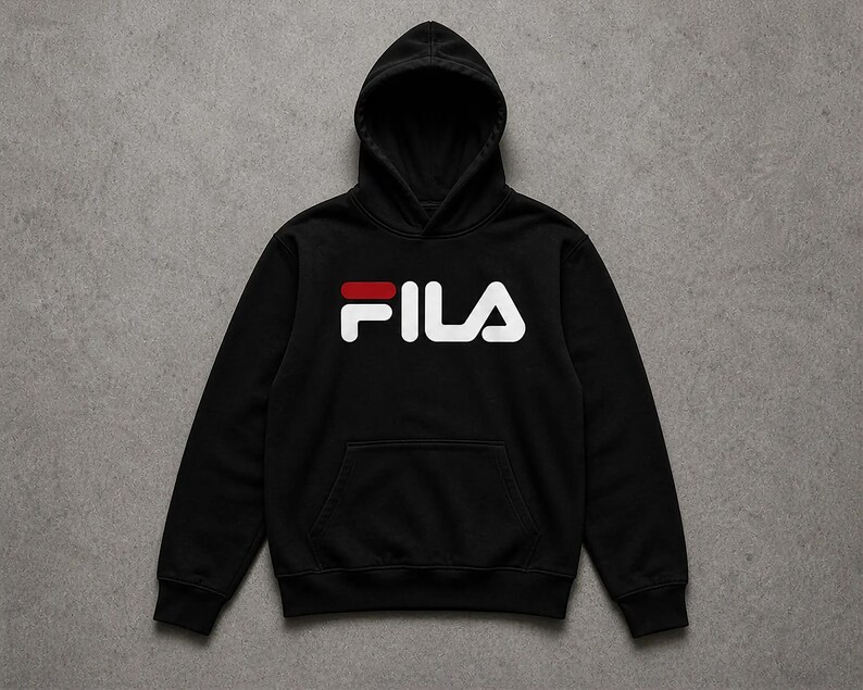 Puede incluir: Sudadera con capucha negra con bolsillo de canguro. La palabra "FILA" est&aacute; impresa en blanco en el pecho, con una barra horizontal roja encima de la "A". La sudadera est&aacute; hecha de un material suave.