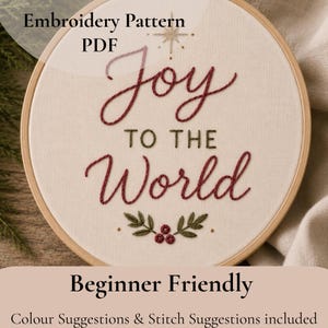 May include: An embroidery pattern PDF featuring the text Joy TO THE World stitched in red and green thread on off-white fabric. The design includes a small star above the text and a holly berry motif at the bottom, all held in a wooden hoop.
