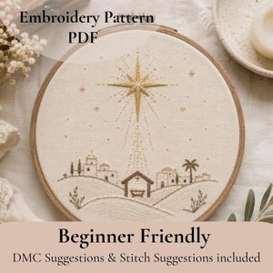 May include: An embroidery pattern PDF featuring a circular wooden hoop containing a beige fabric with a stitched nativity scene. The design includes a large gold star above a small stable, palm trees, and buildings, all rendered in fine thread.