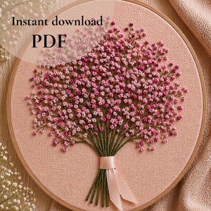 Può includere: Design floreale ricamato in un cerchio di legno. L'opera presenta un bouquet di fiori rosa con steli verdi, legato con un nastro rosa. Lo sfondo è un tessuto rosa chiaro. Il testo sull'immagine recita "Download istantaneo PDF".
