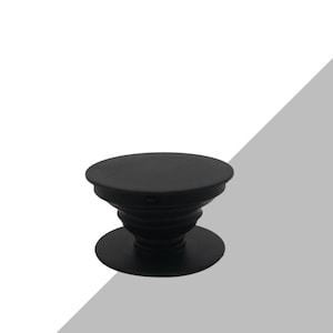 Puede incluir: Un soporte para teléfono negro con una parte superior e inferior circulares, conectadas por una sección extensible en forma de acordeón. Diseñado para fijarse a la parte trasera de un teléfono.