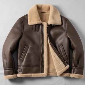 May include: A brown leather jacket with a beige shearling lining and collar. The jacket has a zip closure, two front pockets, and a classic aviator style. The jacket is a medium brown color.