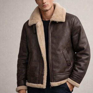May include: A brown leather jacket with a cream-colored shearling lining and collar. The jacket has a zip-up front, two pockets, and shearling trim on the cuffs and hem. A classic outerwear piece.