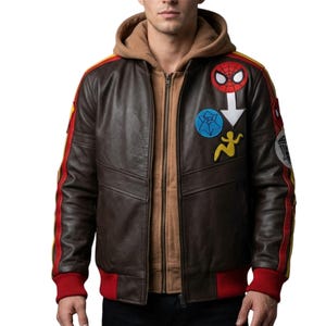 May include: A dark brown leather bomber jacket featuring a tan hooded lining, red ribbed cuffs, and a red and yellow stripe down the sleeves. The chest is decorated with a circular Spider-Man patch, a blue star patch, and a yellow figure patch.