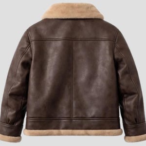May include: A brown leather jacket with a beige shearling collar and trim. The jacket has a classic aviator style with a tailored fit, featuring a smooth, textured finish and a warm, inviting aesthetic.