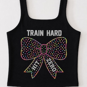 May include: A black tank top featuring the silver text TRAIN HARD above a large bow graphic decorated with multicolored rhinestones. The bow tails contain the silver text HIT and ZERO, completing the design on the front of the garment.