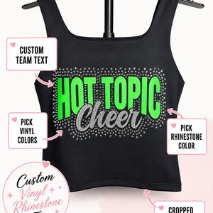 May include: A black cropped athletic top featuring the text HOT TOPIC in bright green and the word Cheer in silver glitter. The design is surrounded by a border of small clear rhinestones. The image includes text boxes with arrows pointing to the design elements.