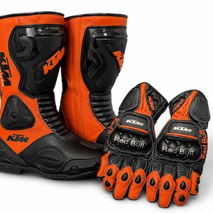 Könnte beinhalten: Orangefarbene und schwarze Motorradstiefel und -handschuhe. Die Stiefel und Handschuhe tragen das KTM-Logo und das Red Bull-Branding. Die Stiefel sind hoch, mit schwarzen Akzenten und Schutzplatten. Die Handschuhe haben Knöchelschutz.